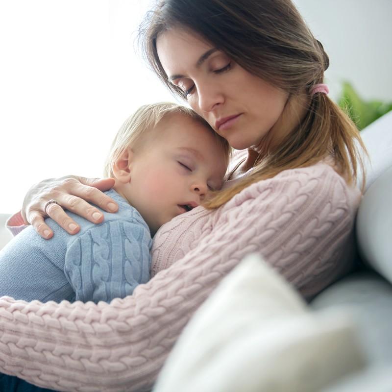 Bebé cansado que no consigue dormirse en brazos de su madre en una habitación tranquila”