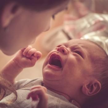 Bebé luchando contra el sueño mientras su madre intenta calmarlo en una habitación tranquila